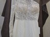 wedding dress hanging on a hanger in front of a white wall