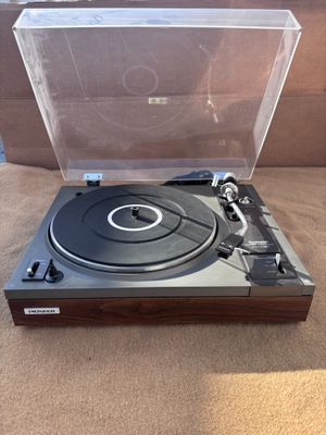 un gros plan d'un tourne-disque posé sur une table, avec son étui