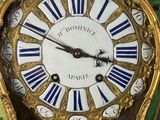 a green and gold clock with roman numerals on it