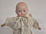 a small doll that is standing on a white surface
