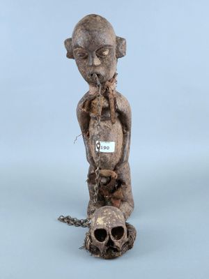 une vieille statue en bois représentant un homme avec une chaîne autour du cou