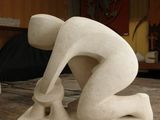 a statue of a man bending over on a wooden table