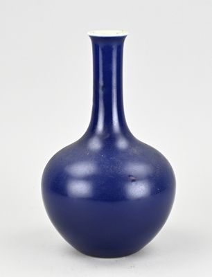 un vase bleu posé sur une surface blanche