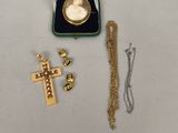 une croix en or et une pièce d'or dans une boîte verte