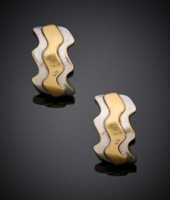 une paire de boucles d'oreilles en or et en argent posées sur un fond noir