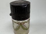 a small glass jar with a black lid on a white surface