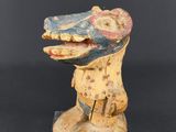 une sculpture en bois représentant une tête de serpent posée sur un socle transparent
