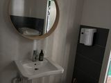 une salle de bains équipée d'un lavabo, d'un miroir et d'un distributeur de serviettes