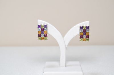 a pair of multicolored stone earrings on a white stand