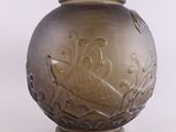 un vase brun orné d'un motif sur une surface blanche