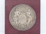 plaque représentant les armoiries de deux hommes et d'une femme sur un fond rouge