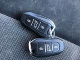 two car keys sitting on the seat belt of a car