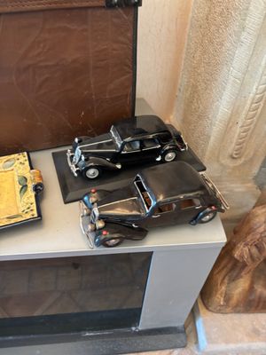 deux petites voitures posées sur une table, à côté d'une valise