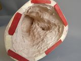 un gros plan sur une sculpture en argile représentant un visage, posée sur une table