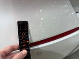 a hand that is holding a ruler in front of a car