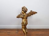 an antique brass statue of a child with wings on a wooden floor