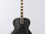 a black acoustic guitar sitting on top of a white surface