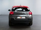 the rear of a small grey car with a red tail light