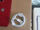 a red iphone sitting on top of a box next to a charger