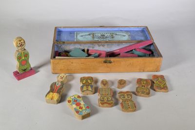 une boîte en bois remplie de jouets en bois posée sur une surface blanche