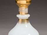 an image of a white glass bottle with a gold top