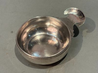 a silver bowl with a spoon in it on a table