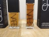 two bottles of nars cosmetics sitting on a table next to each other