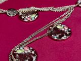 two necklaces with flowers on a chain on a pink surface