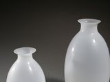 two white vases sitting next to each other on a table