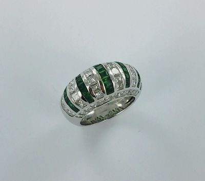 gros plan d'une bague en diamant et émeraude sur fond blanc