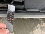 a person holding a ruler in front of the front bumper of a car