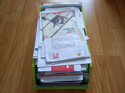 une boîte remplie de courrier posée sur un plancher en bois