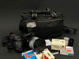 un sac noir contenant un appareil photo, un objectif et d'autres objets, posé sur une table