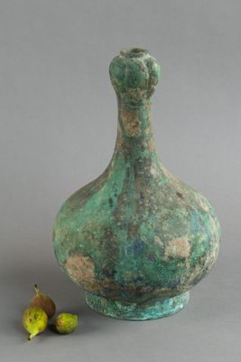 un vase vert avec une poire à côté