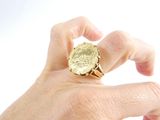a person holding a gold ring with a coin on it