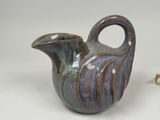 a blue and brown vase sitting on a white surface