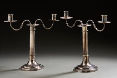 pair of silver plated candelabs with candles on stands