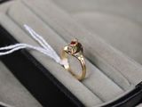 une bague en or sertie d'une pierre rouge, dans un écrin