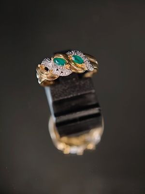 deux bagues en or ornées d'émeraudes et de diamants sur un fond noir