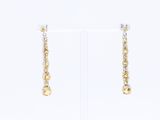 boucles d'oreilles en or et en argent posées sur un présentoir blanc, sur fond blanc