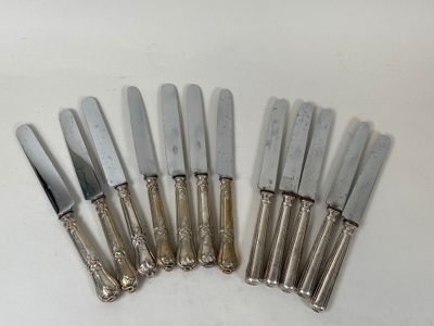 six silverplated knives are lined up in a row on a white surface