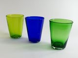 three different colored glasses sitting next to each other on a table