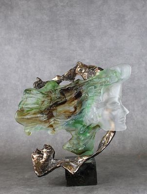 sculpture représentant le visage d'une femme, ornée d'une feuille verte, posée sur un socle en marbre