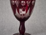 a wine glass with a house on it sitting on a table