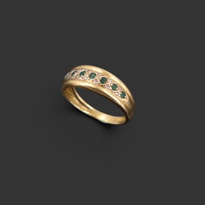 une bague en or sertie d'émeraudes et de diamants sur fond noir