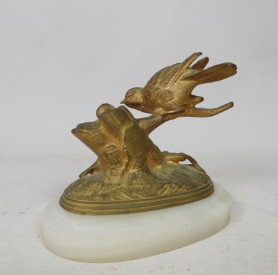 une statue en or représentant un oiseau, posée sur un socle en marbre