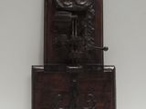 une horloge ancienne en bois, dotée d'un cadran sculpté et posée sur un socle