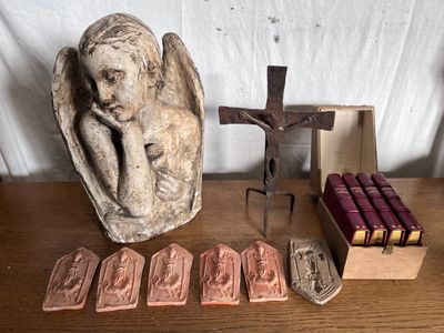 une statue d'ange à côté d'un crucifix et d'une boîte de bougies