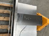 une photo d'une scie à table posée sur une palette dans un entrepôt