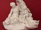 a white statue of a woman and two children on a rock